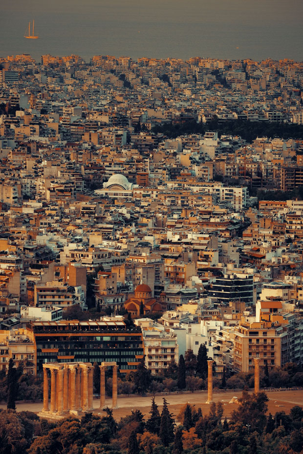 Sky view over Athens Greece with the Saronic Gulf in the distance, with orange tinted lights from sunset coming on Sky view over Athens Greece with the Saronic Gulf in the distance, with orange tinted lights from sunset coming on